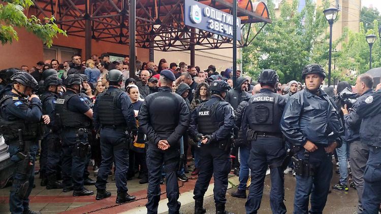 Polizisten halten aufgebrachte Serben im Ort Zvecan zurück.