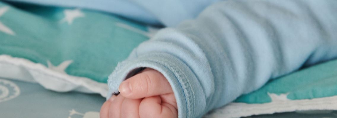 Ein wenige Wochen altes Baby ballt seine Hand zu einer kleinen Faust.