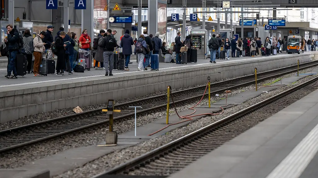 Passagiere-warten-auf-einen-der-wenigen-verkehrenden-Fernzuege-der-an-einem-Bahnhof-eintreffen-soll