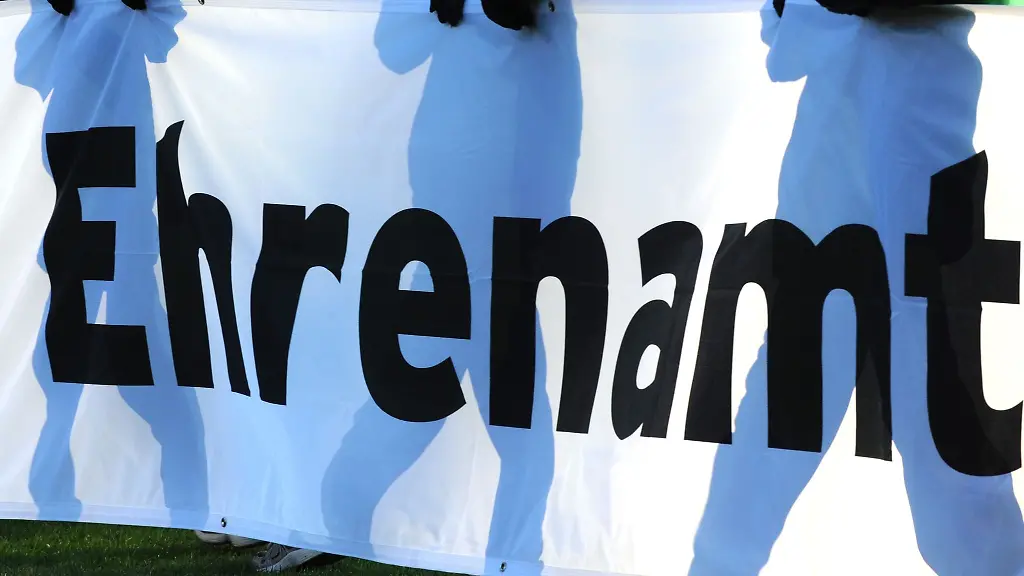 Jugendliche-halten-vor-einem-Fussball-Bundesligaspiel-ein-Banner-mit-der-Aufschrift-Ehrenamt-in-den-Haenden