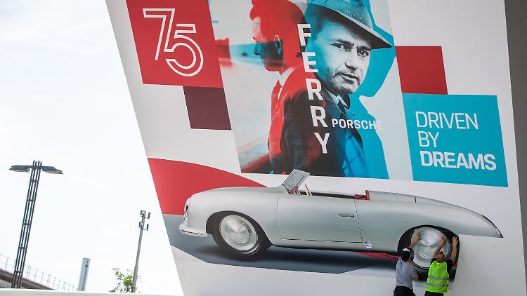 Zum 75-jährigen Bestehen des Sportwagenbauers: Arbeiter bekleben die Fassade des Porsche-Museums mit einer Werbebande, auf dem der erste Porsche und Ferdinand Porsche zu sehen sind.