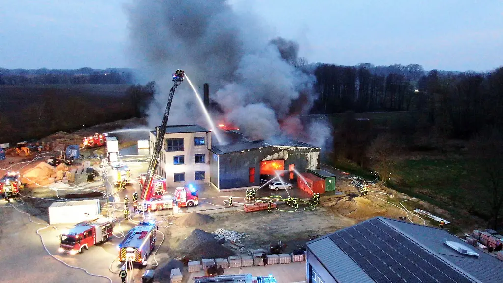 Einsatzkraefte-der-Feuerwehr-loeschen-den-Grossbrand-einer-Gewerbehalle-in-Alfhausen