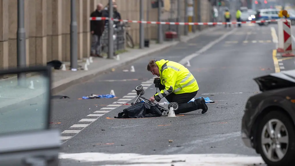 Ein-Polizist-kniet-an-der-Unfallstelle-neben-dem-zerstoerten-Kinderwagen