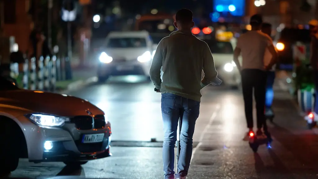 E-Scooter-fahren-in-der-Nacht-durch-eine-Strasse