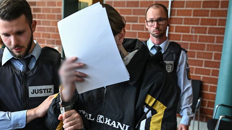 Der Angeklagte wird von Justizmitarbeitern in den Gerichtssaal geführt.