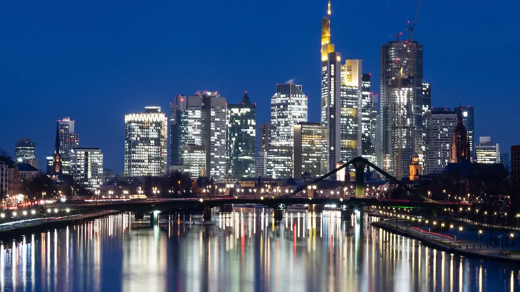 Die-Lichter-der-Bankenskyline-von-Frankfurt-am-Main-leuchten-im-letzten-Licht-des-Tages