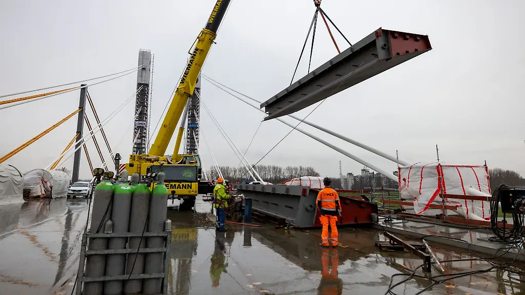 Ein-schwerer-Kran-transportiert-ein-tonnenschweres-Metallteil-auf-der-neuen-Rheinbruecke
