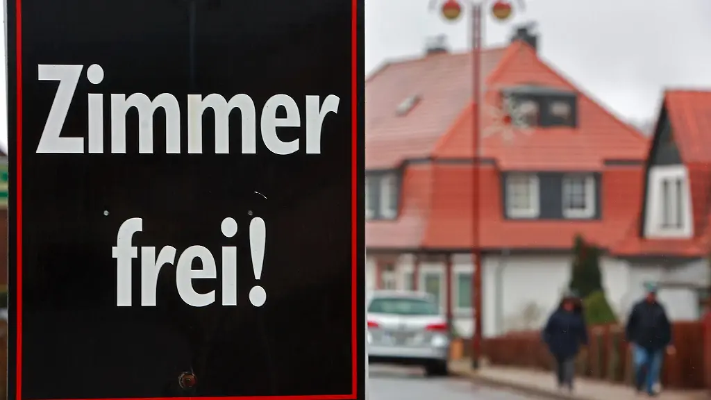 Ein-Aufsteller-mit-der-Aufschrift-Zimmer-frei-steht-vor-einer-Pension