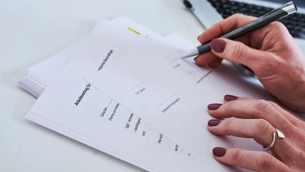 Eine-Frauenhand-unterschreibt-einen-Arbeitsvertrag