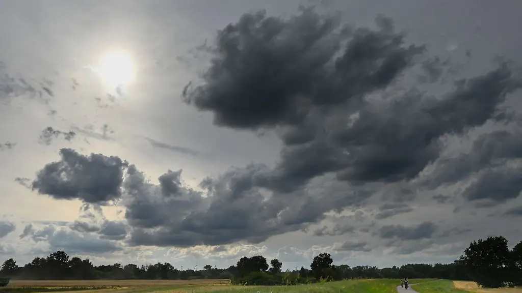 Ein-dunkler-Wolkenhimmel-ueber-dem-Radweg-und-Deich-in-der-Muldeaue