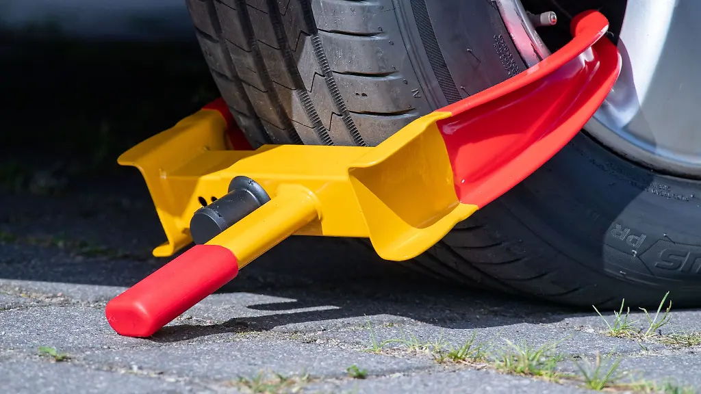 Eine-Parkkralle-mit-Sicherheitsschloss-ist-an-einem-Autoreifen-auf-einem-Parkplatz-montiert