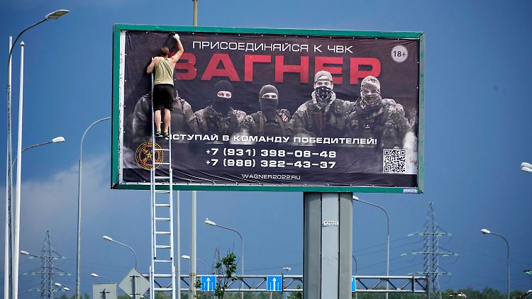 In St. Petersburg wird ein Plakat, das für die Wagner-Armee wirbt, abgerissen.
