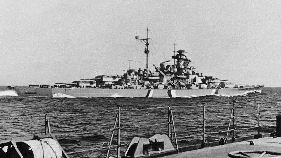Das Schlachtschiff Bismarck im Jahr 1941. Bug und Heck des Schiffes sind dunkel gestrichen. An der Längsseite wurden künstliche Wellen gemalt.