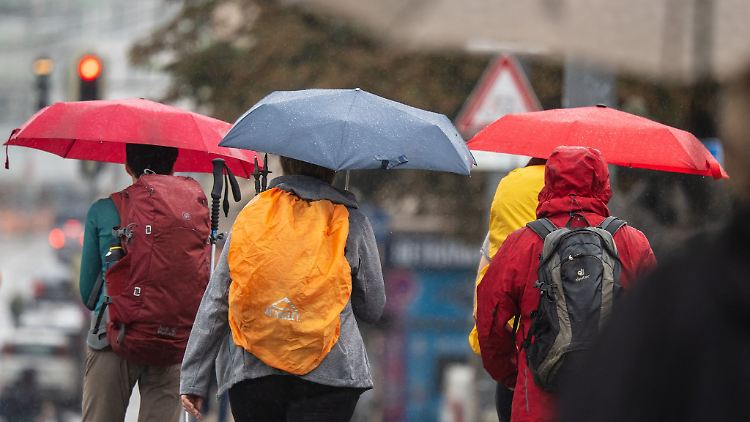 Menschen schützen sich bei Regen mit ihren Schirmen.