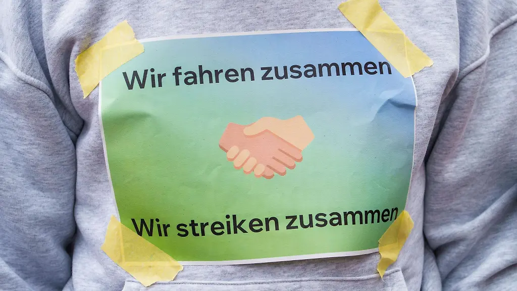 Ein-Kundgebungsteilnehmer-hat-sich-ein-Schild-Wir-fahren-zusammen-Wir-streiken-zusammen-auf-die-Brust-geklebt