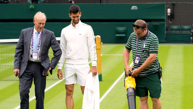 Novak Djokovic lächelt, der Laubbläser bläst.