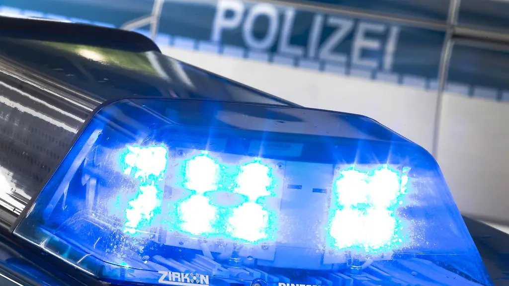 Eine-Blaulicht-leuchtet-auf-dem-Dach-eines-Polizeiwagens-Im-Hintergrund-steht-ein-weiterer-Streifenwagen