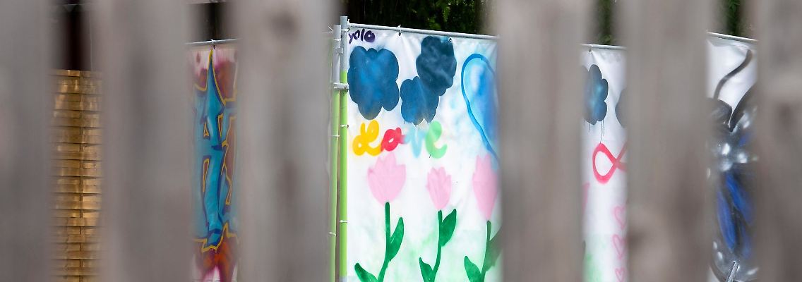 Am Rand einer Brachfläche hängen von Kindern gestaltete Plakate an Bauzäunen. An dieser Stelle stand das Haus, vor dem der Messerangriff auf zwei Schülerinnen stattfand.