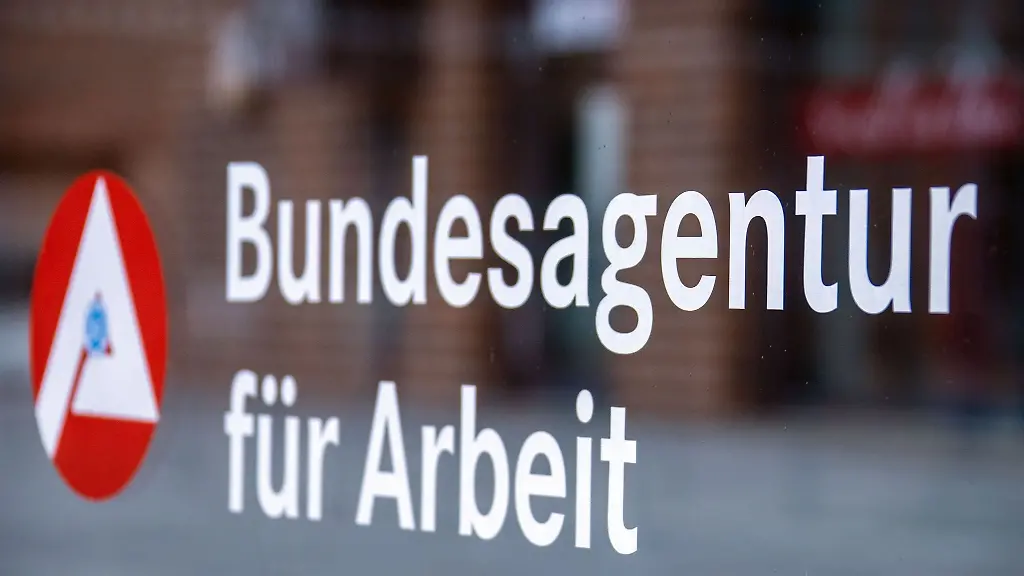 Das-Hinweisschild-fuer-die-Bundesagentur-fuer-Arbeit-ist-an-einer-Glasflaeche-vor-einem-Buerogebaeude-zu-sehen