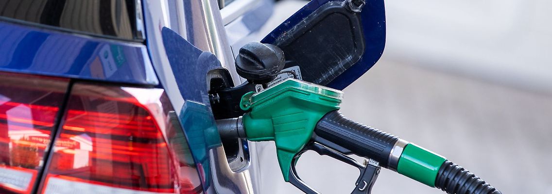 Eine Zapfpistole steckt an einer Tankstelle in einem Wagen.