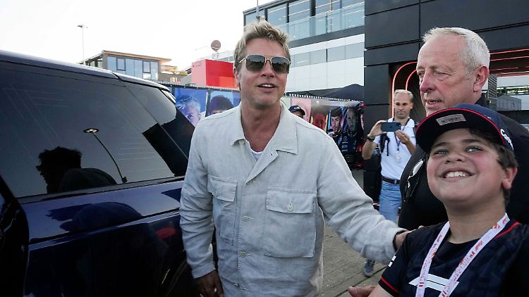 Schauspieler Brad Pitt lächelt den Fans zu, die das Fahrerlager verlassen.