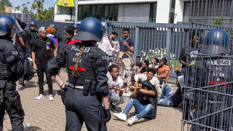 Polizisten umringen vor Beginn der Veranstaltung eine Gruppe von Menschen.