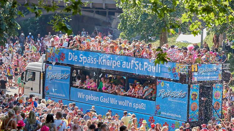 Schlagerfans ziehen bei strahlendem Sonnenschein durch die Hamburger Innenstadt.