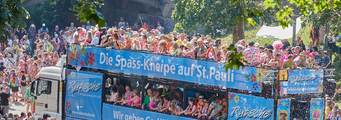 Schlagerfans ziehen bei strahlendem Sonnenschein durch die Hamburger Innenstadt.