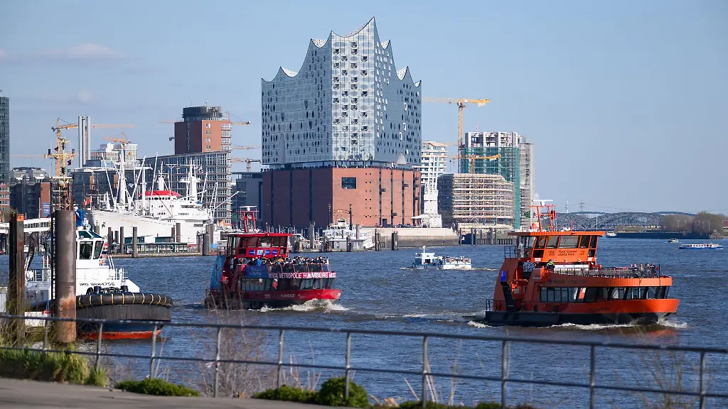 Hafenfaehren-der-HADAG-fahren-im-Sonnenschein-auf-der-Elbe-vor-den-Landungsbruecken-der-Elbphilharmonie-und-der-Hafencity