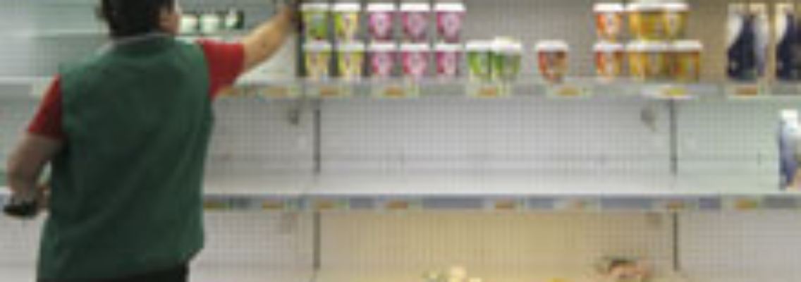 Die Mitarbeiterin eines Supermarktes entfernt belastete Milchprodukte aus den Regalen.