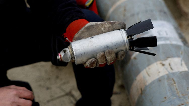 Ein ukrainischer Soldat hält einen entschärften Teil einer Streubombe in der Hand, die von Russland eingesetzt wurde.