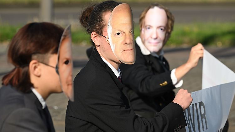 "Wir brechen das Gesetz" steht auf dem Banner, das Aktivisten mit Scholz-, Wissing- und Habeck-Masken in Berlin hochhalten.