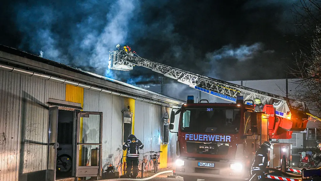 Mitarbeiter-der-Feuerwehr-loeschen-einen-Brand-in-einer-Asylbewerberunterkunft