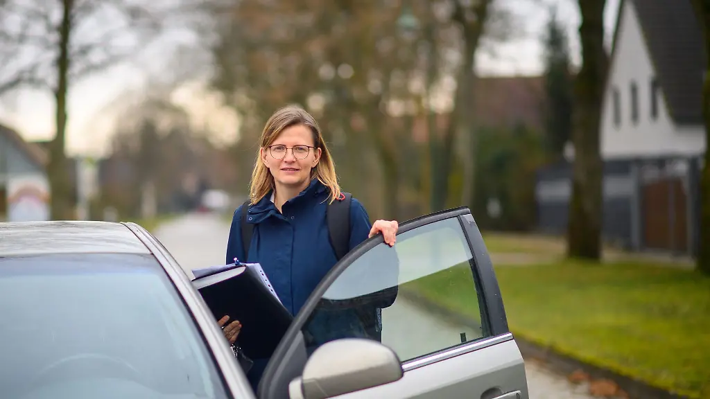 Pflegebegutachterin-Jeannine-Mittendorf-steigt-in-einem-kleinen-Ort-vor-einem-Haus-aus-ihrem-Auto-aus