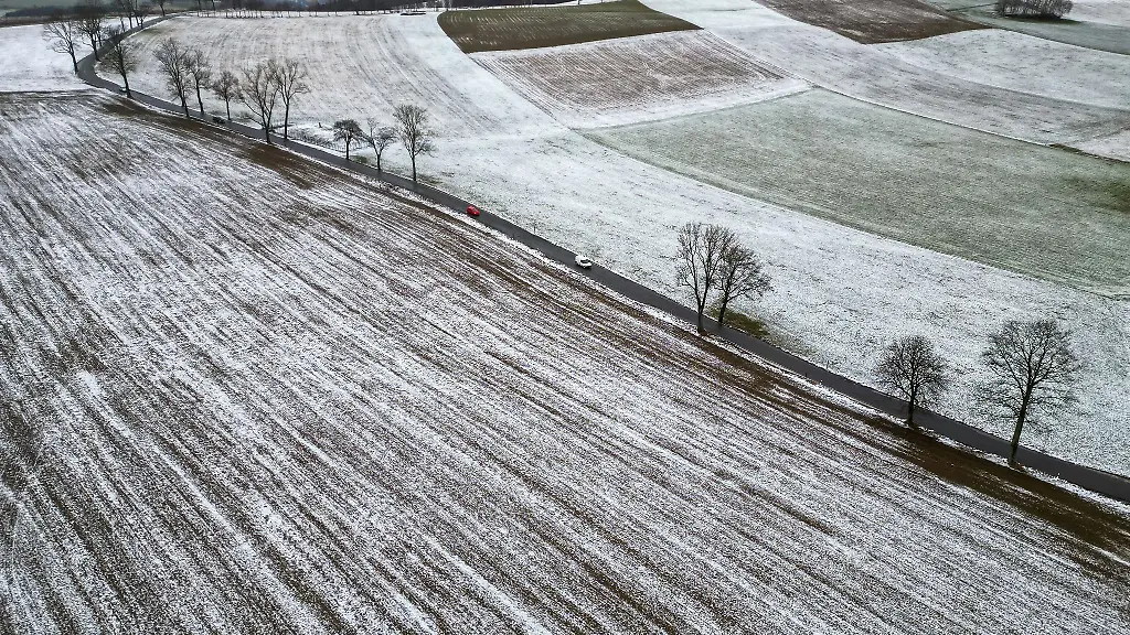 Autos-fahren-ueber-eine-Strasse-im-leicht-verschneiten-Erzgebirge