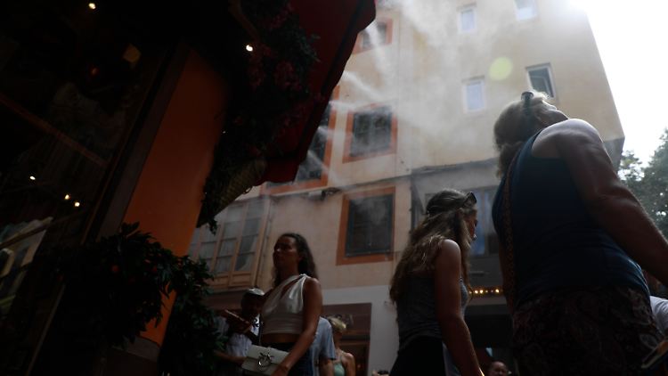 In einer Einkaufsstraße in Palma wird Wasser verspritzt.