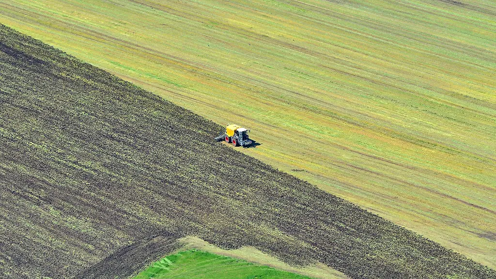 Eine-Landwirtschaftsmaschine-bringt-bei-Bad-Aibling-in-Bayern-Guelle-auf-ein-gemaehtes-Feld-auf