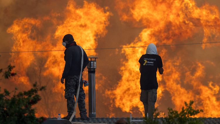 Anwohner Gennadis stehen auf ihren Dächern vor riesigen Flammen und versuchen mit Wasserschläuchen ihre Häuser zu retten.