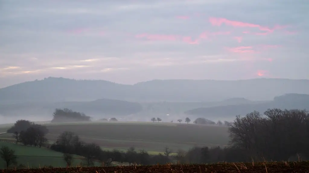Blick-ueber-eine-neblige-Landschaft-in-Itzgrund-mit-Morgenrot-am-Himmel