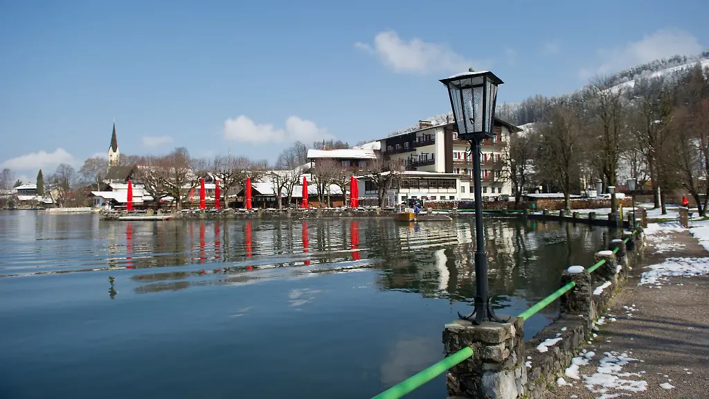 Die-Kirche-und-Haeuser-spiegeln-sich-im-Wasser-des-Schliersees