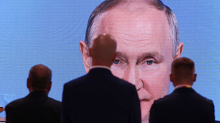 Männer schauen auf einen Bildschirm, der Putins Ansprache  bei der Plenarsitzung des Russisch-Afrikanischen Wirtschafts- und Humanitären Forums überträgt. 