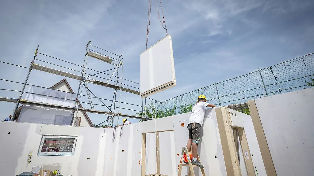 Ein-Bauarbeiter-steht-auf-einer-Leiter-und-arbeitet-im-Rohbau-eines-Fertighauses