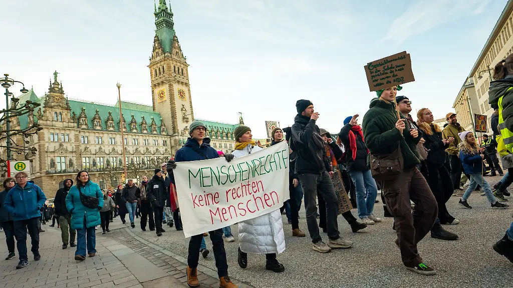 Demonstranten-ziehen-mit-Plakaten-unter-anderem-mit-der-Aufschrift-Menschenrechte-keine-rechten-Menschen-vor-dem-Rathaus-entlang
