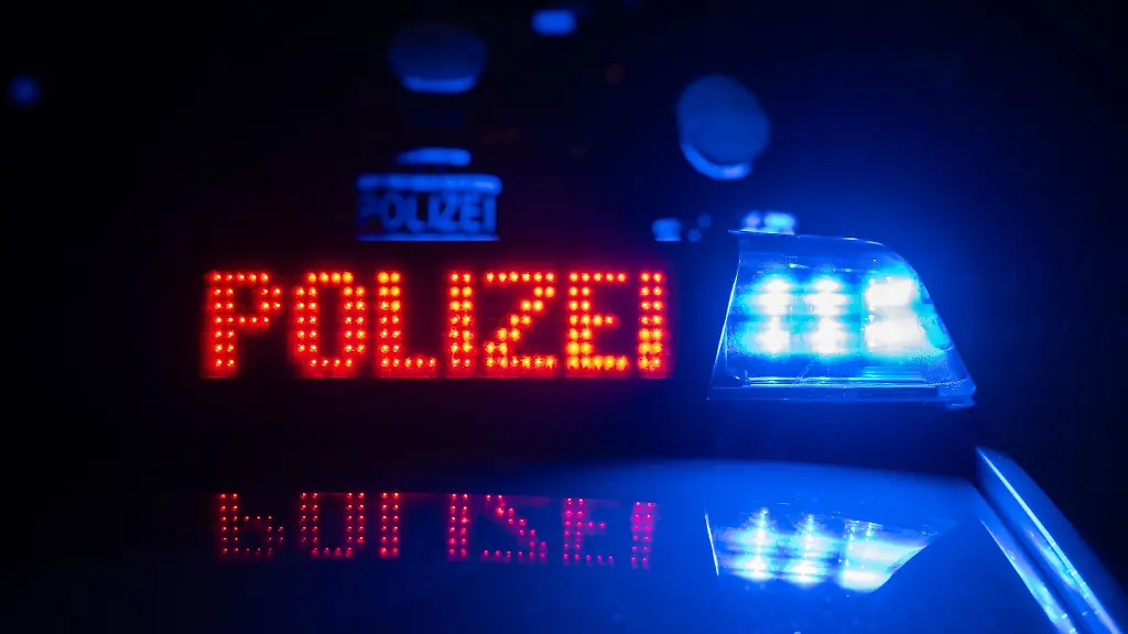 Zwei-Polizisten-stehen-vor-einem-Polizeifahrzeug