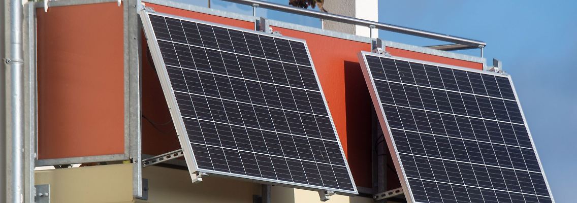Solarmodule für ein sogenanntes Balkonkraftwerk hängen an einem Balkon.