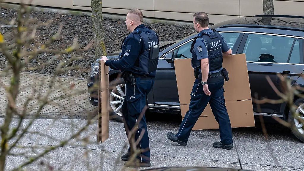 Zollbeamte-mit-Umzugskartons-laufen-an-einem-durchsuchten-Gebaeude-vorbei