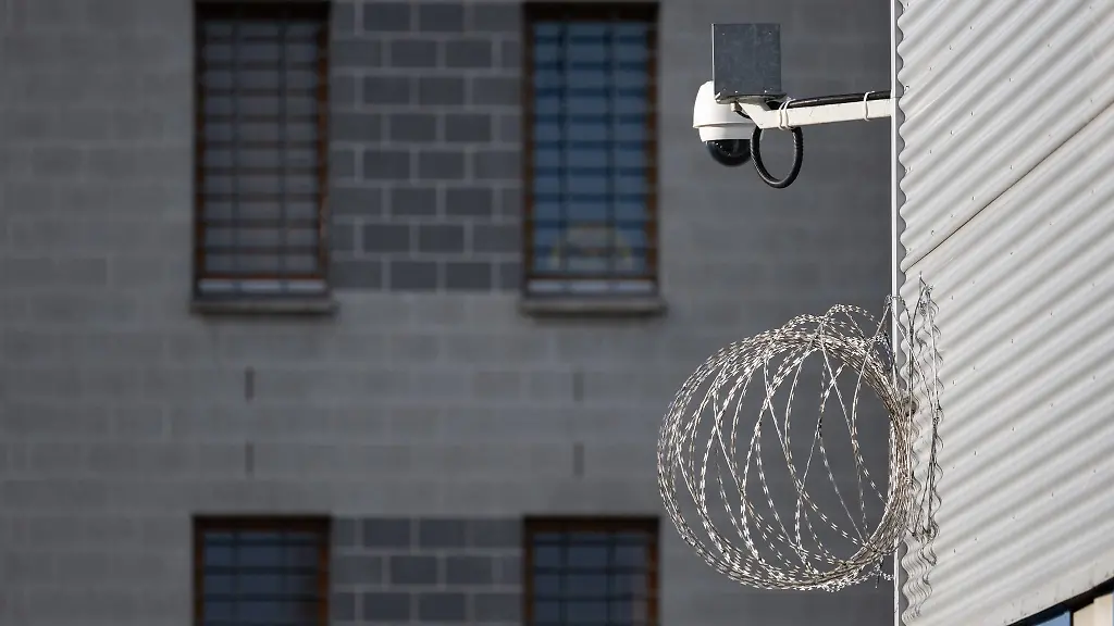 Eine-Videoueberwachungsgeraet-und-Stacheldraht-sind-im-Hof-der-JVA-Dresden-an-einem-Gebaeude-montiert