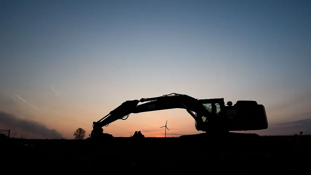Ein-Bagger-steht-bei-Sonnenaufgang-an-einem-Neubaugebiet