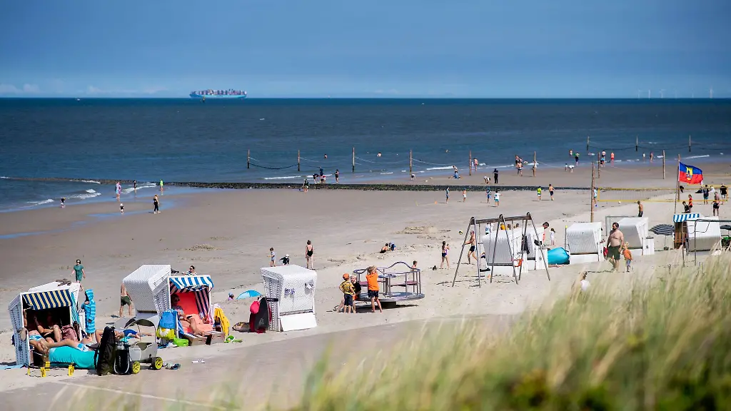 Touristinnen-und-Tourstien-sitzen-bei-sonnigem-Wetter-in-Strandkoerben-am-Strand-der-Insel-Wangerooge