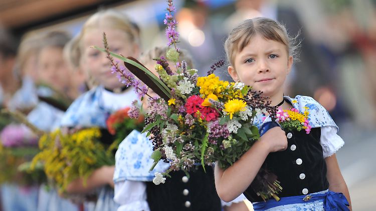 Mädchen in Tracht tragen an Mariä Himmelfahrt ihre Kräuterbuschen in die Kirche.